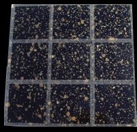 Nine 25x25mm black with gold-coloured speckles MF8 mirror mosaic tiles photographed in bright sunlight.